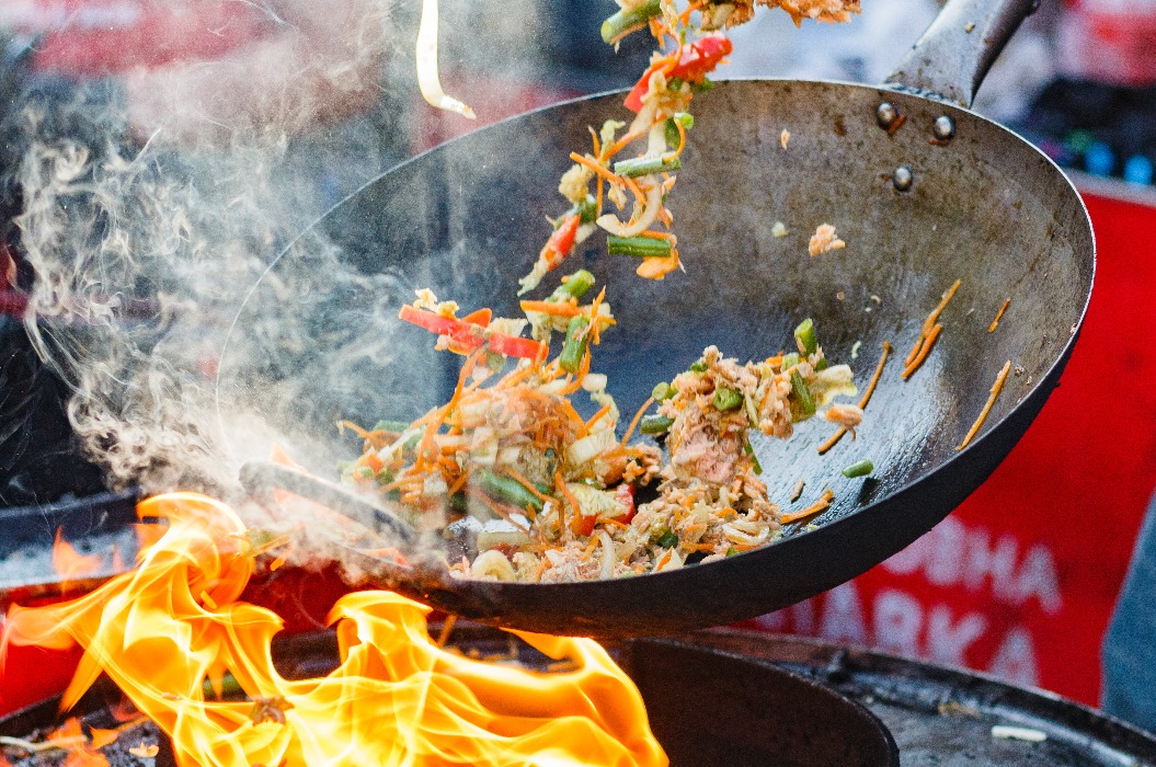 Koch bereitet chinesische Nudeln im Wok auf einem Streetfood-Festival zu